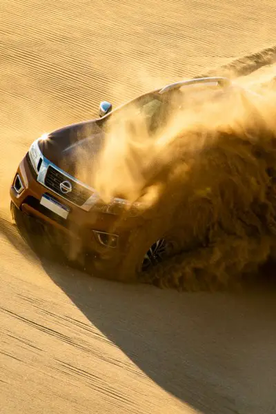 Red Nissan running on sand dune